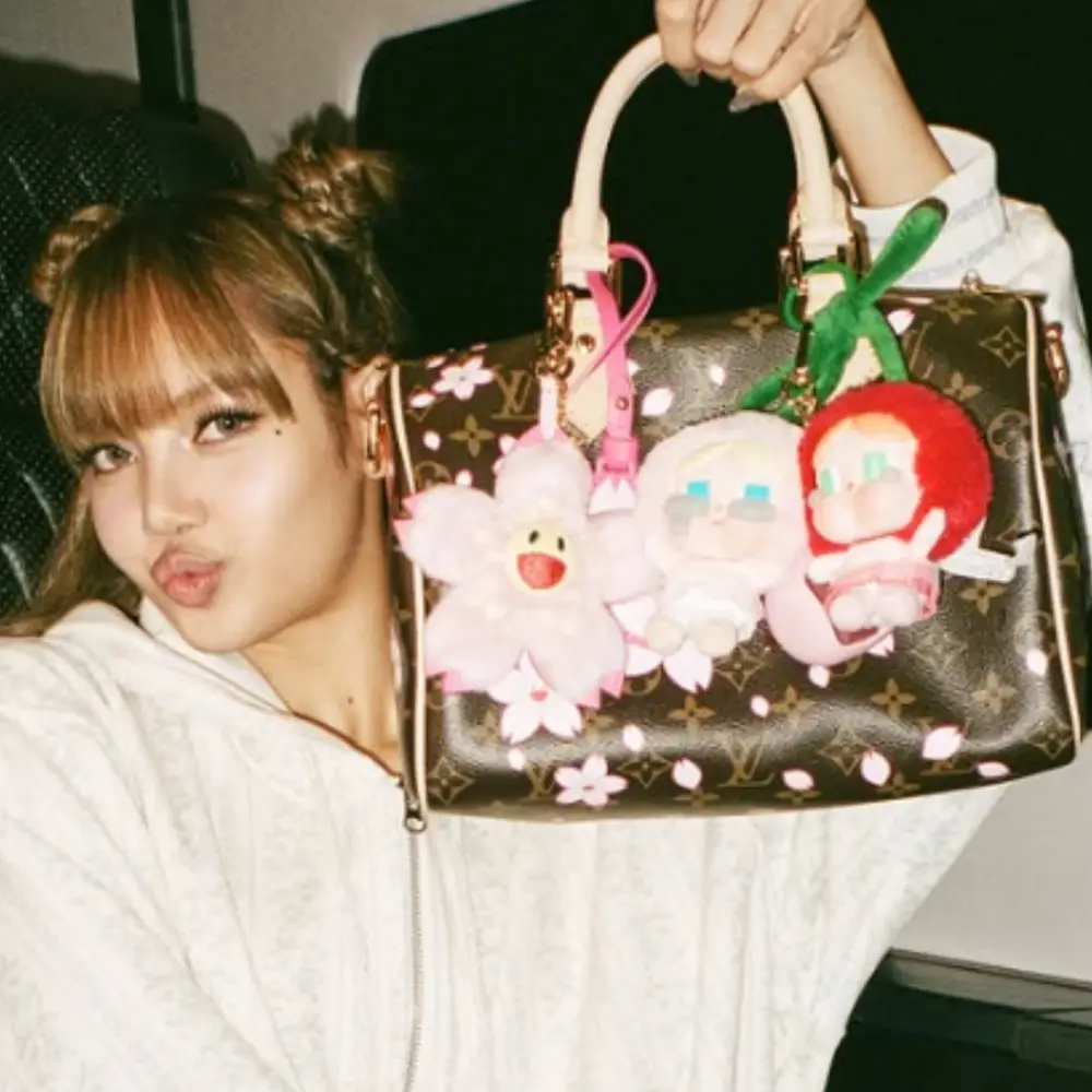 Blackpink Lisa tenant un sac à main orné de porte-clés peluches colorées style kawaii